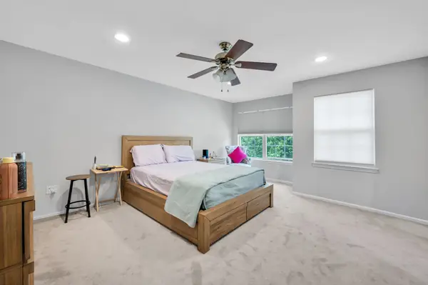 Primary bedroom with ceiling fan and garden-view windows