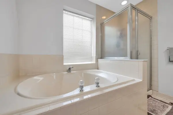 Primary bath corner soaking tub beside the glass stall shower